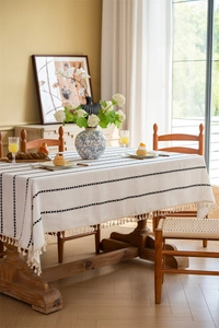 Close-up of white polyester tablecloth featuring black diamond patterns and tassels