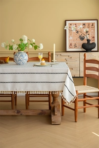 Close-up of geometric jacquard patterns and fine tassel fringe on cream tablecloth