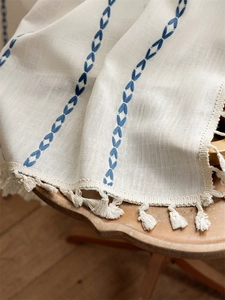 Detailed view of jacquard geometric embroidery and fringe on the woven linen fabric