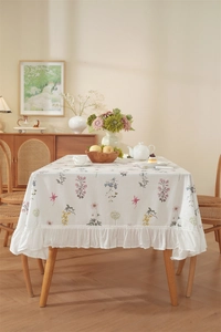 Close-up of floral print cotton tablecloth featuring white ruffles and a nature-inspired design