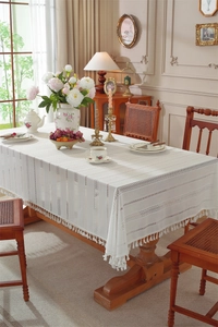 Detailed close-up of French white lace tablecloth with hollow patterns and fringe tassels