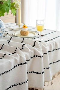 Detailed view of cream jacquard tablecloth with black bow embroidery and fringe tassels