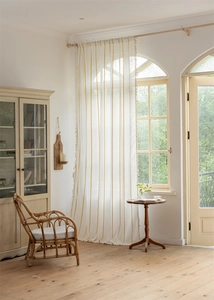 Detailed view of white semi-sheer curtain featuring yellow chain embroidery and elegant tassels