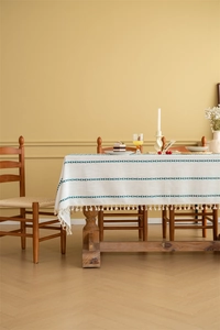 Close-up of green geometric jacquard pattern and fringe edge on a beige tablecloth