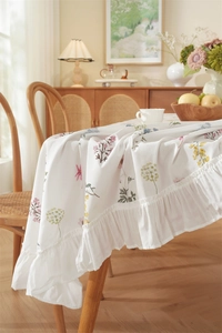 Detailed view of white floral cotton tablecloth with elegant ruffled edge for home decor
