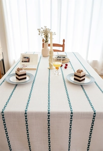 Detail of off-white tablecloth with navy blue leaf embroidery and elegant textured fringe