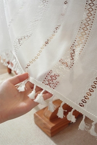 Detailed view of white lace tablecloth showing hollow geometric patterns and fringe tassels
