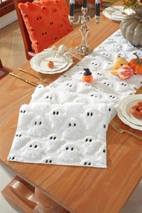 Detail of plush white Halloween table runner featuring embroidered black ghost patterns