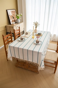 Detailed view of beige polyester tablecloth with green stripes and cotton tassel fringe