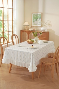 Detailed close-up of a floral cotton tablecloth with elegant ruffled edge and blue patterns