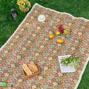 Retro bohemian floral jacquard picnic mat with white tassels on a lush green lawn