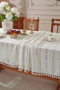 Close-up of white bohemian crochet lace tablecloth with elegant fringe trim detail