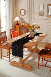Detail of black plush Halloween table runner with white ghost embroidery and decor