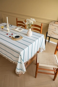 Detailed view of cream jacquard tablecloth with green leaf embroidery and fringed edges