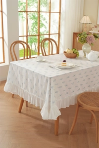 Detail of floral ruffle edge tablecloth with light blue leaf patterns on cotton fabric