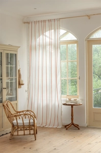 Detail of bohemian curtain with orange embroidery stripes and delicate tassel trim