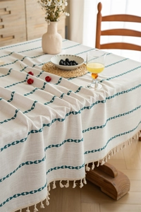 Detail of Nordic style woven tablecloth fabric with navy embroidery and cream tassels