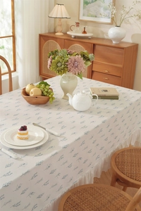 Close-up of cream floral tablecloth with light blue leaf pattern and pleated ruffle edges