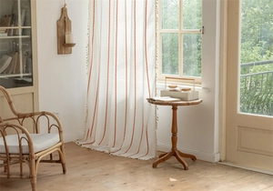 Close-up of white polyester curtain featuring orange geometric stripes and tassel edges