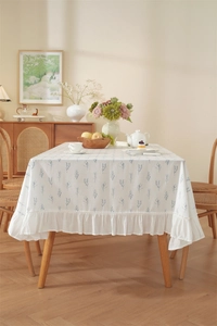 Detailed view of white floral tablecloth with delicate ruffled edges in a cozy room