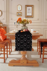 Detail of black plush Halloween table runner with white ghost eyes in a festive setting