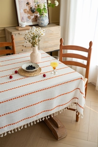 Macro detail of Nordic table runner showing orange embroidered stripes and cotton tassels