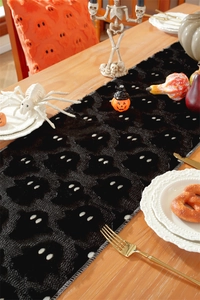 Detailed embroidery of white ghosts on black Halloween table runner with spooky decor