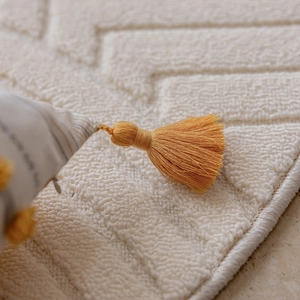 Detail of beige jacquard pillowcase with geometric tufted texture and fringe edges