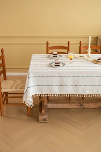 Close-up of cream rectangle tablecloth with blue geometric patterns and fringe tassels