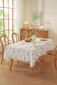 Close-up of small floral print cotton tablecloth with elegant white fringe tassel detail