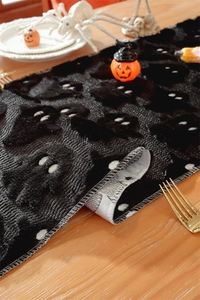 Close-up of black ghost table runner with textured embroidery and white stitched edges