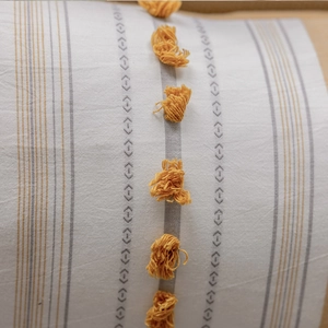 Macro detail of Nordic cotton cushion cover featuring yellow tassels and geometric patterns