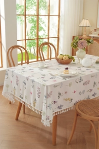 Detail of floral cotton tablecloth featuring green leaf patterns and elegant white fringe