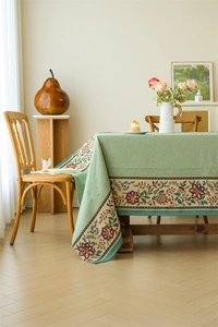 Close-up of vintage Morandi green tablecloth featuring intricate floral embroidery and texture