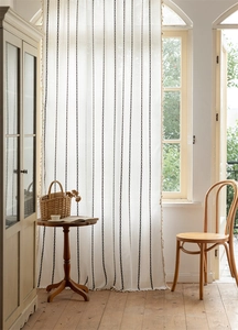 Detail of bohemian geometric curtains with black dashed lines and elegant fringe tassels