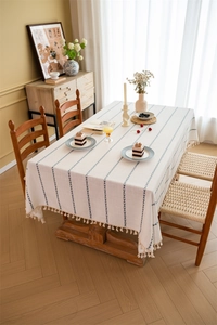 Close-up of beige tablecloth with blue geometric stripes and handmade hanging tassels