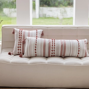 Detail of pink and beige striped cotton pillow cover with boho fringe and pom-poms