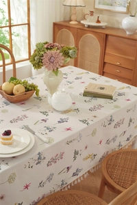 Detail of floral cotton tablecloth featuring tassels and elegant botanical prints