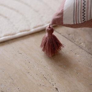 Detail of red stripe fabric with elegant fringe tassel on washed cotton pillowcase