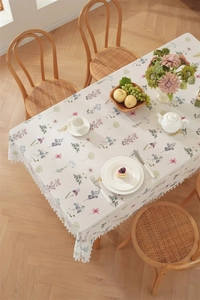 Close-up of floral cotton tablecloth with delicate white pom-pom fringe and edge detail