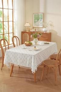 Detailed close-up of cotton floral tablecloth with blue plant prints and tassel fringe