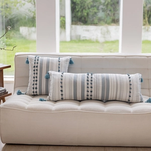 Close-up of Nordic style pillow with blue tassels and vertical stripes on a sofa