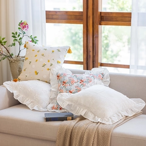 French romantic cotton pillowcases with floral embroidery and ruffle edges on sofa