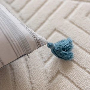 Detailed macro view of the invisible zipper and light blue tassel on the striped pillow cover