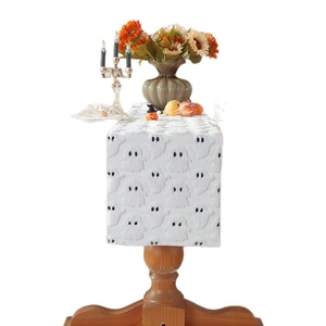 White Halloween table runner with black plush ghost embroidery on a wooden table