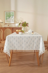 Detailed view of cream cotton tablecloth with blue leaf print and white tassel edges