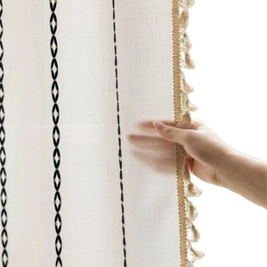 Cream linen-textured curtain with black geometric embroidery and tassel trim details
