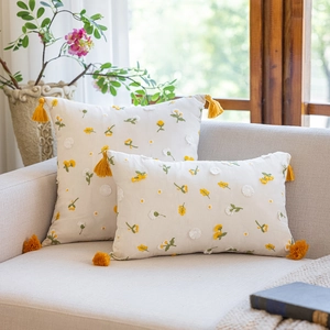 Macro detail of French romantic floral embroidery and yellow tassels on white cotton pillow