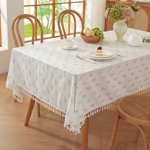 Floral cotton tablecloth with green leaf prints and white tassels in a cozy dining setting