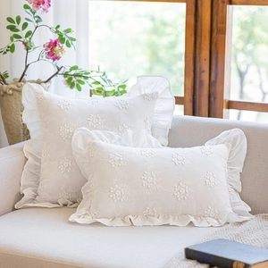 Close-up of white cotton pillowcase with delicate floral embroidery and elegant ruffles